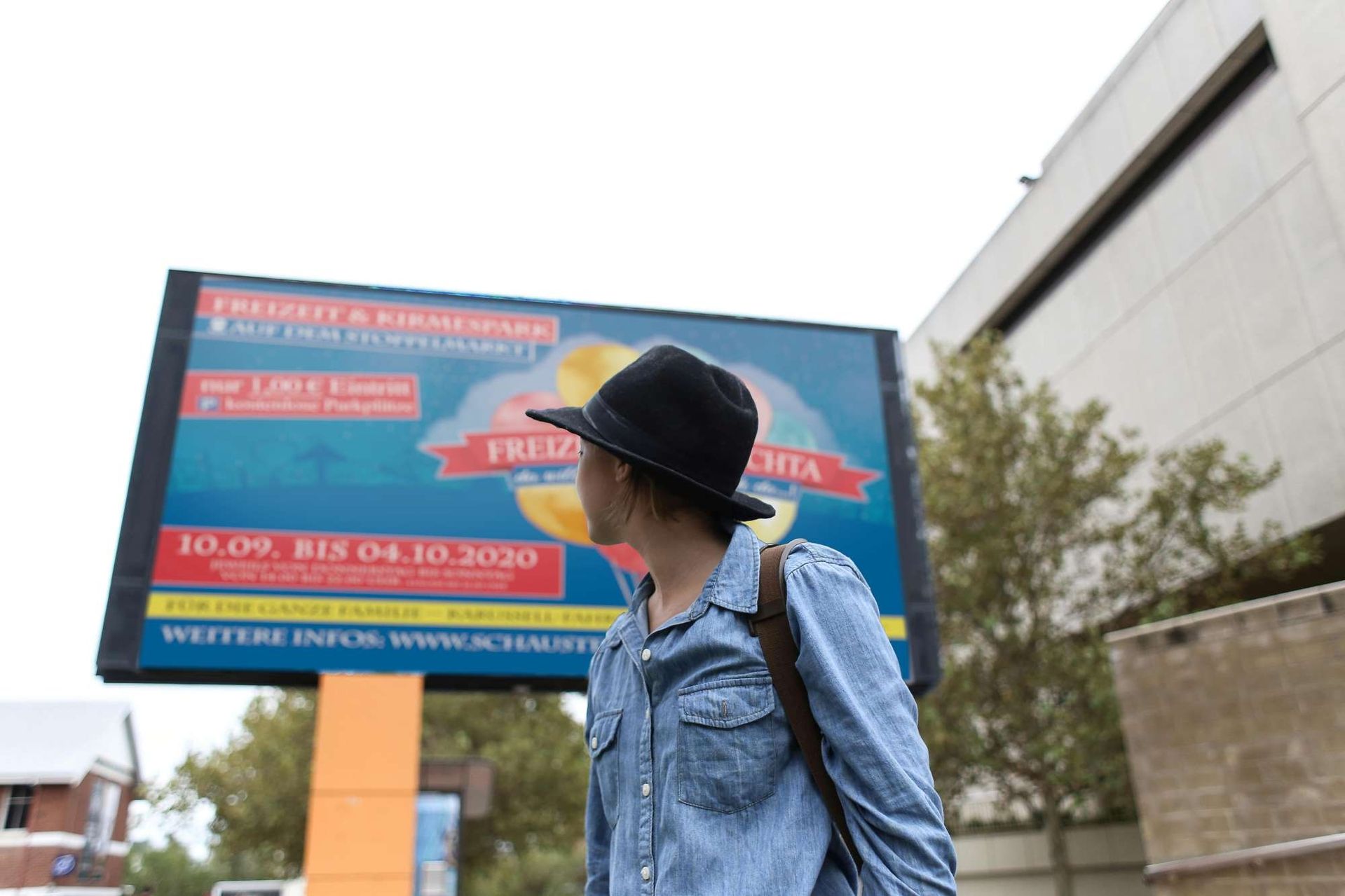 Junge Frau Steht vor einem Plakat auf offener Straße